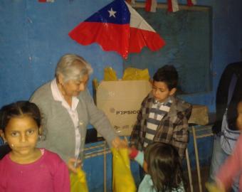 Niños y niñas que reciben unos regalos.
