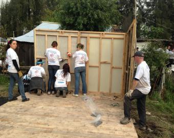 Estudiantes montando los muros de una casa
